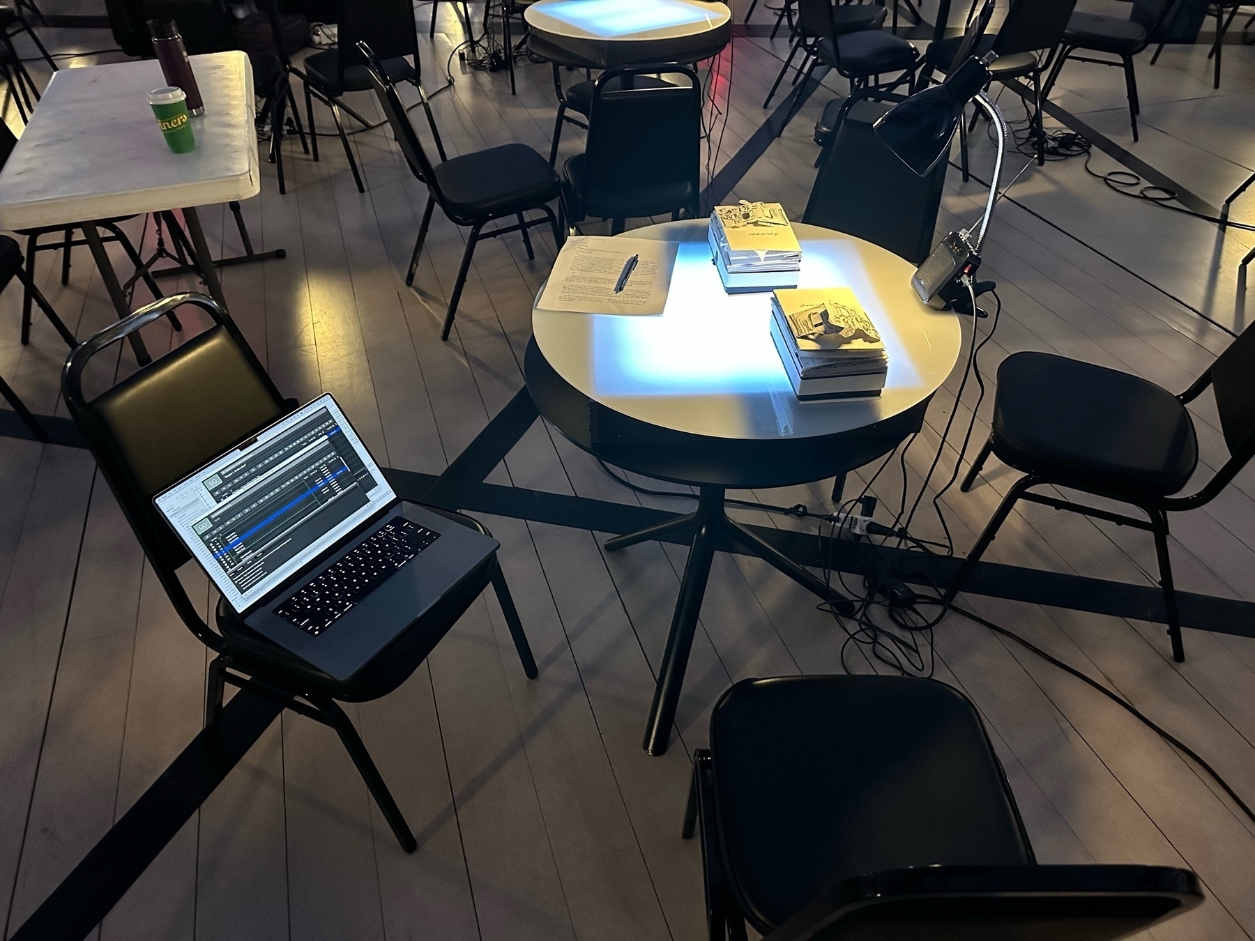 Photo of laptop on chair and books on a glowing table.