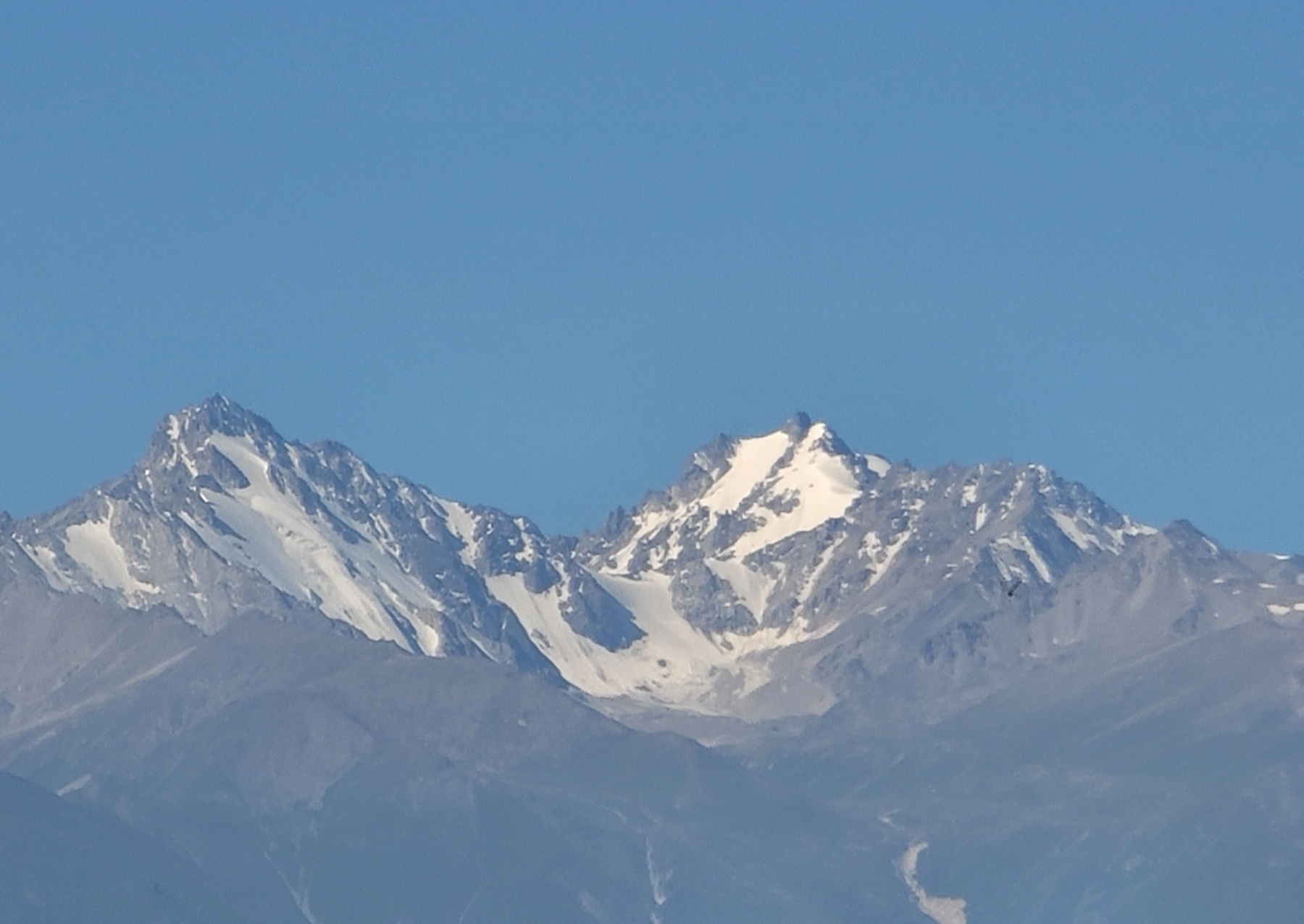 gray mountains with white peaks against a light blue sky