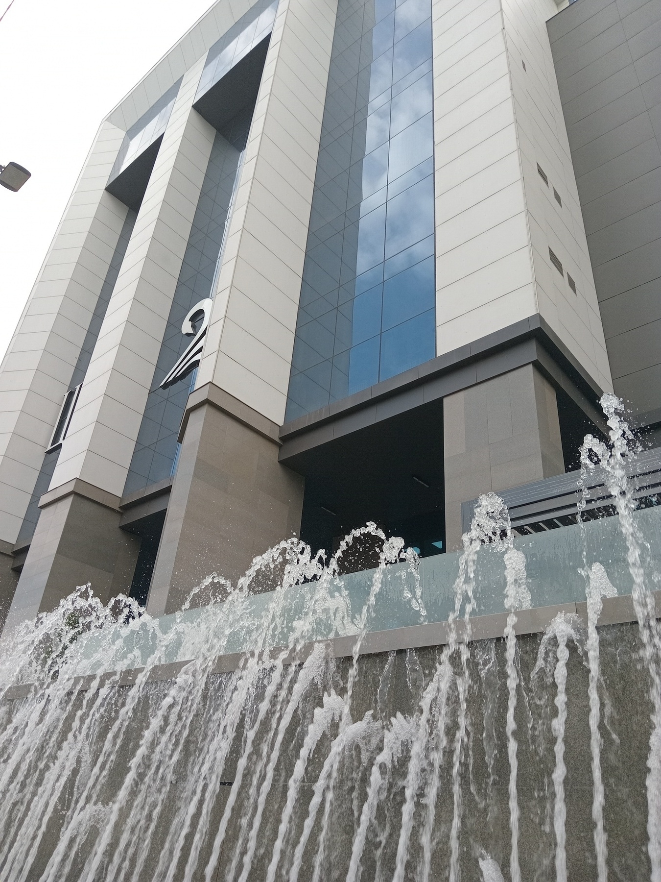 multiple streams of water shooting up from a rectangular fountain in front of a modern building