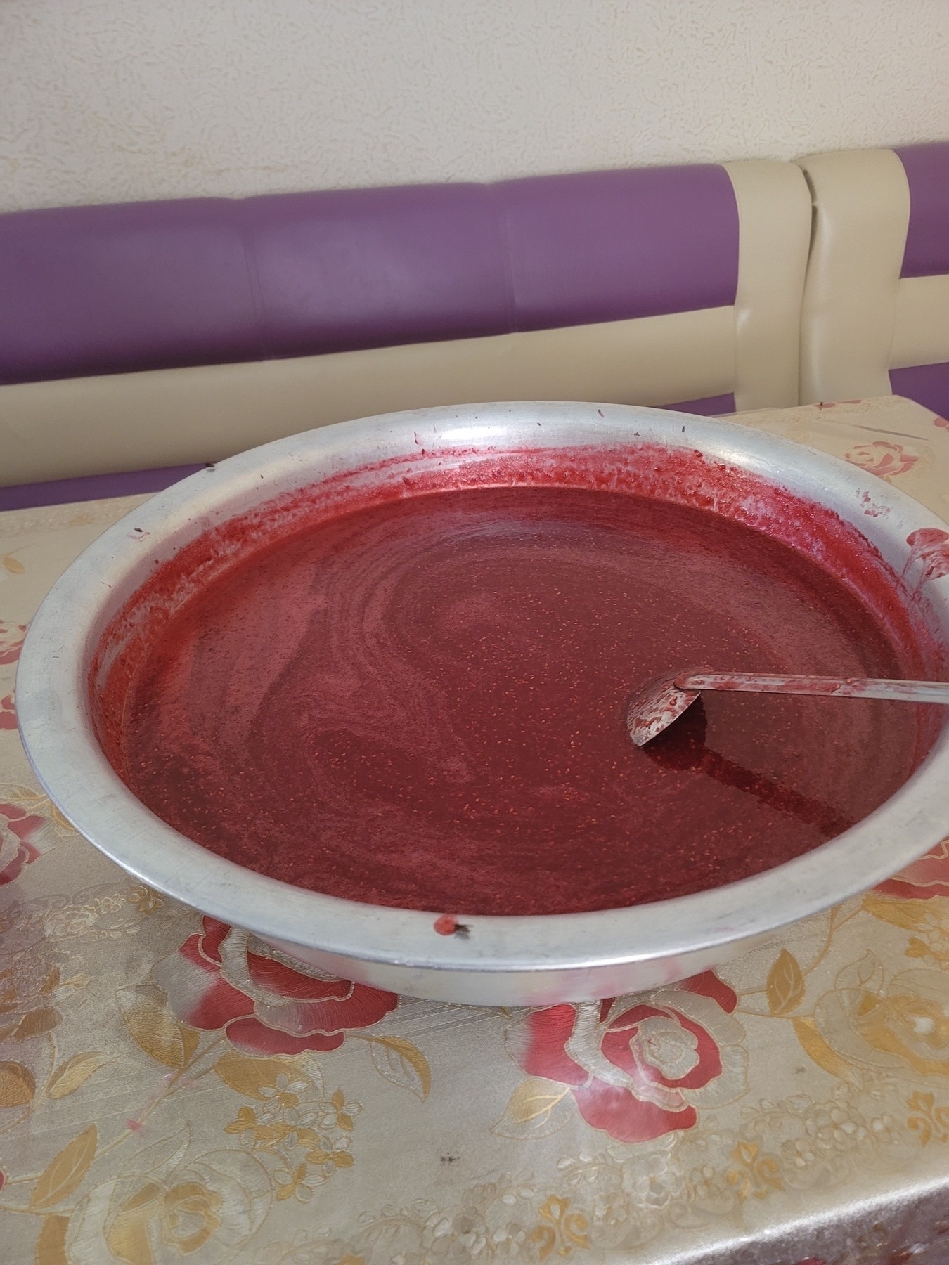 large metal bowl of raspberry jam with a serving utensil in it