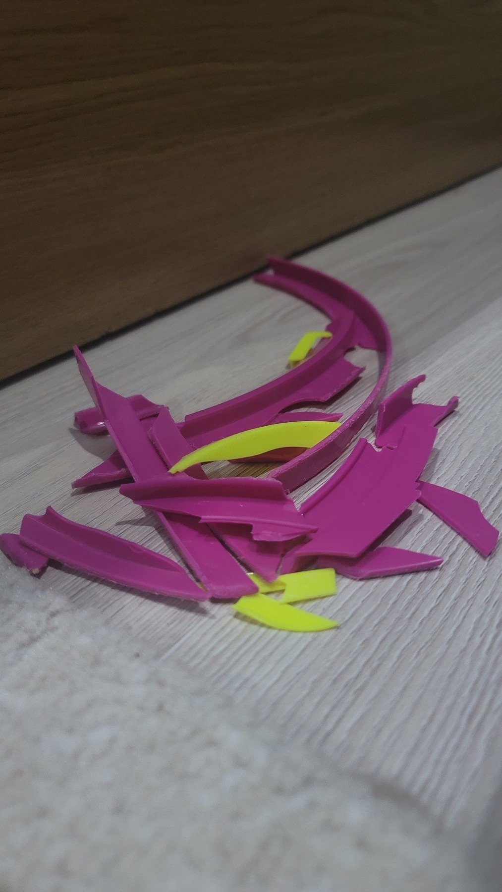 about 7 rounded, pink and 4 rounded, yellow plastic pieces in a pile on the floor