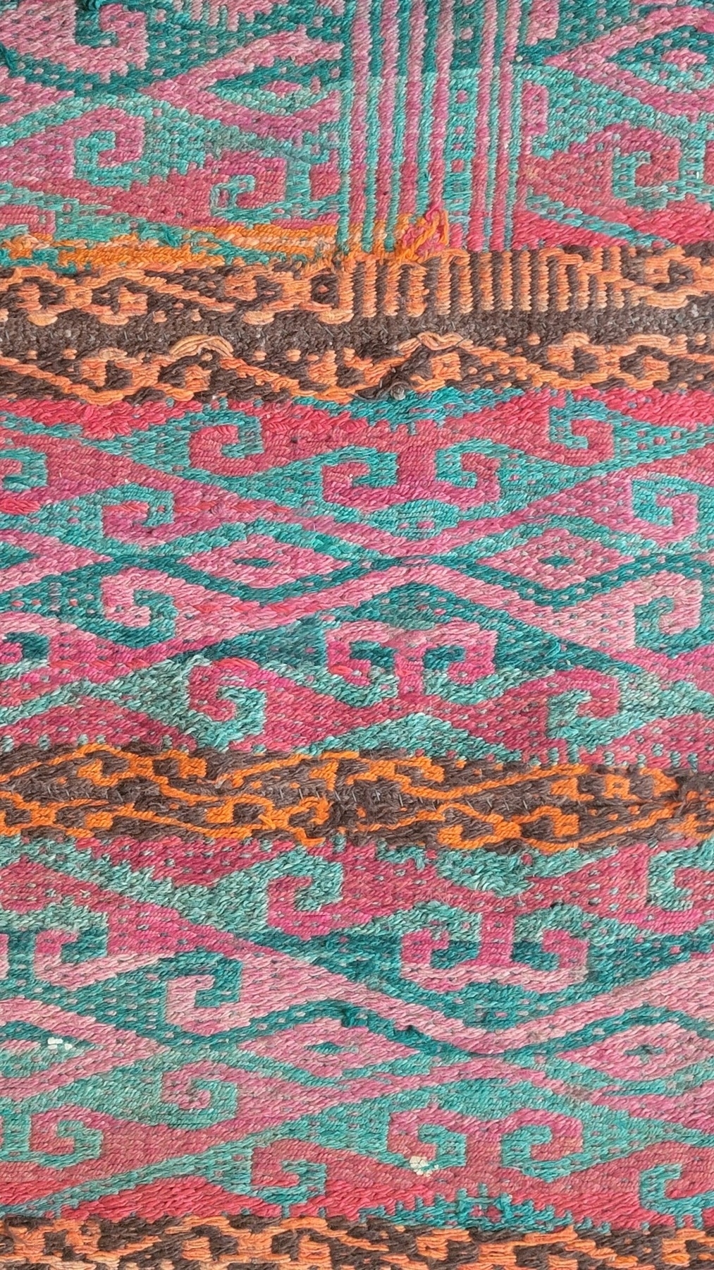 zoom-in of a patterned rug with orange, brown, red and green