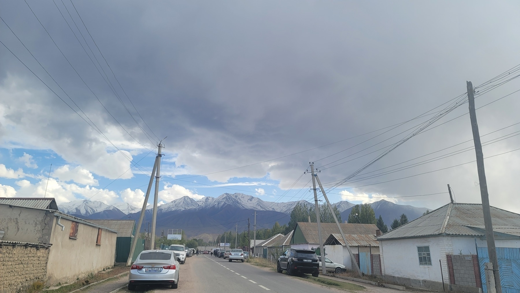 road with houses and power lines on both sides; mountains in the distance. a cloudy day
