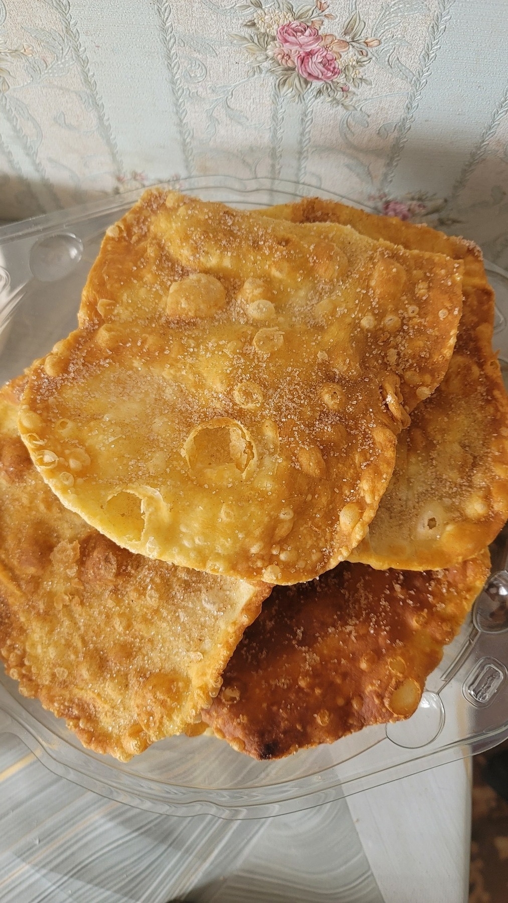buñuelos (fried chips covered with cinnamon and sugar) in a plastic cake lid on a table