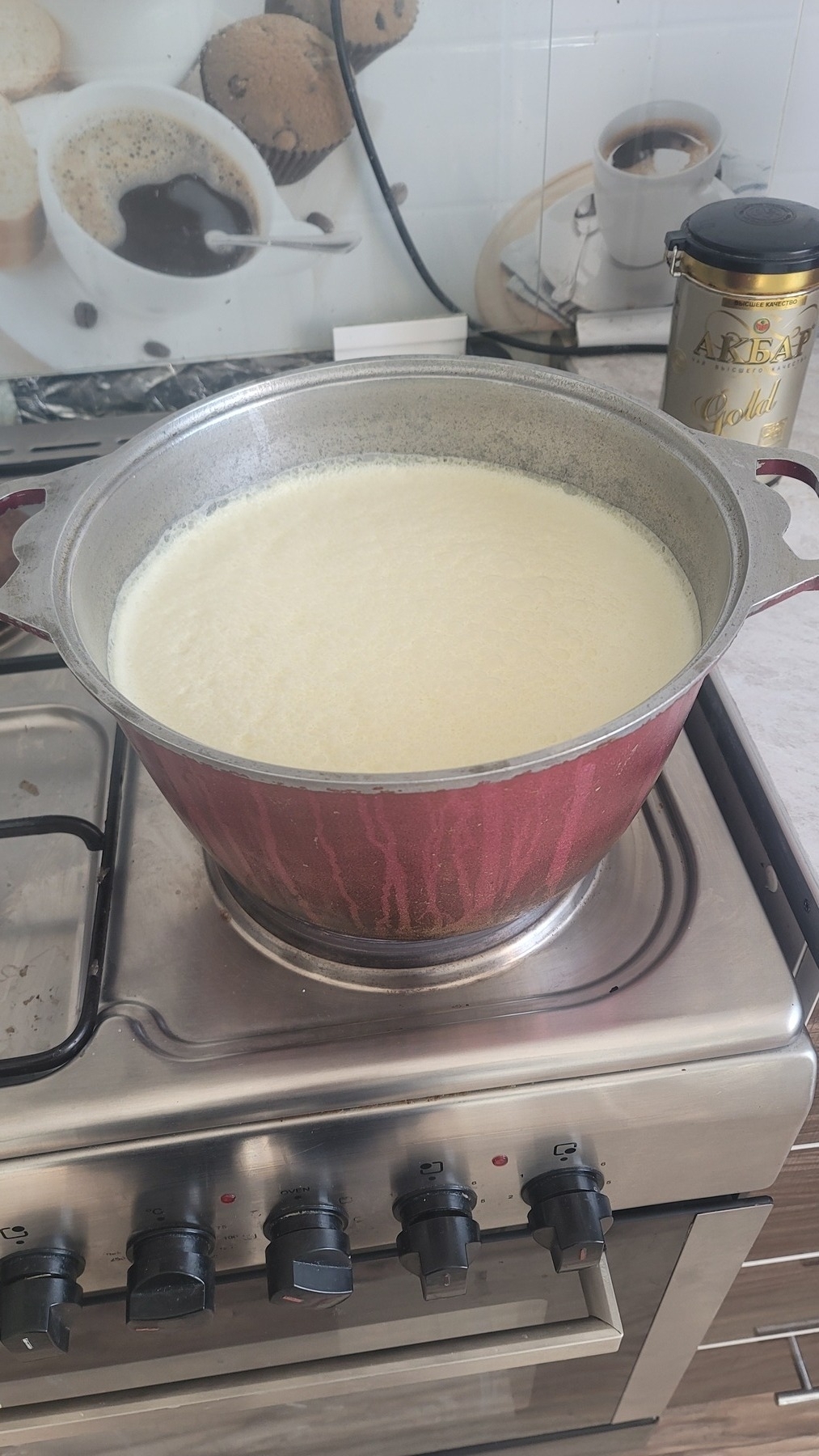 milk in a big pot, gray inside and red outside, on the stove