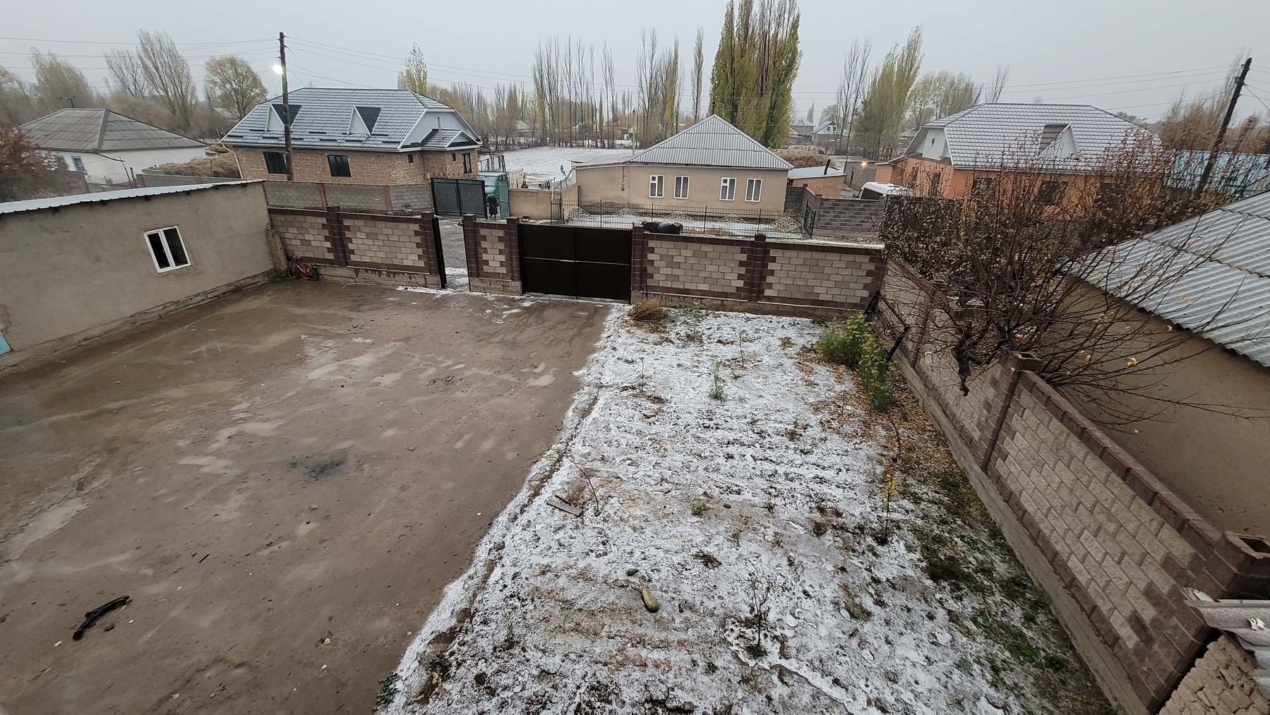 looking down at the yard and street from a second floor window, snow on the grassy parts of the ground