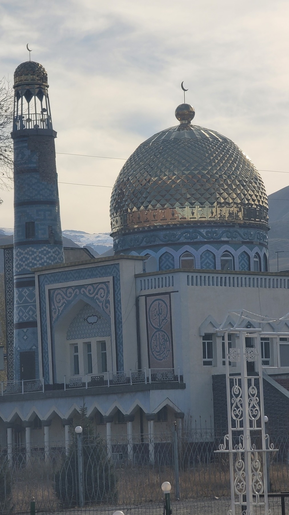 zoom in of a mosque with a golden dome roof and white and blue decoration