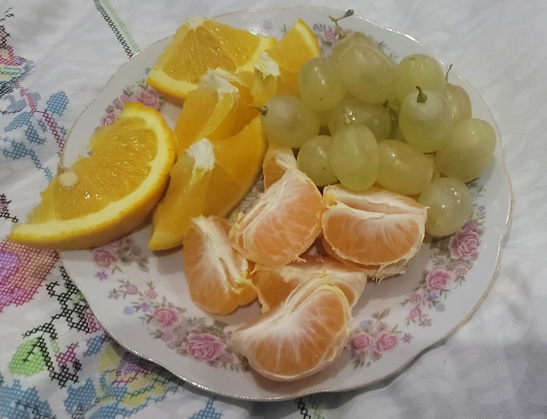 plate with orange slices, tangerine slices and green grapes
