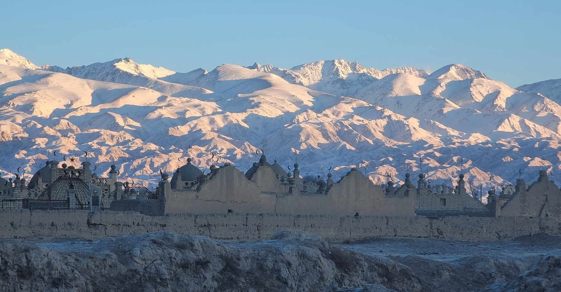 islamic cemetery in front of light pink/white mountains