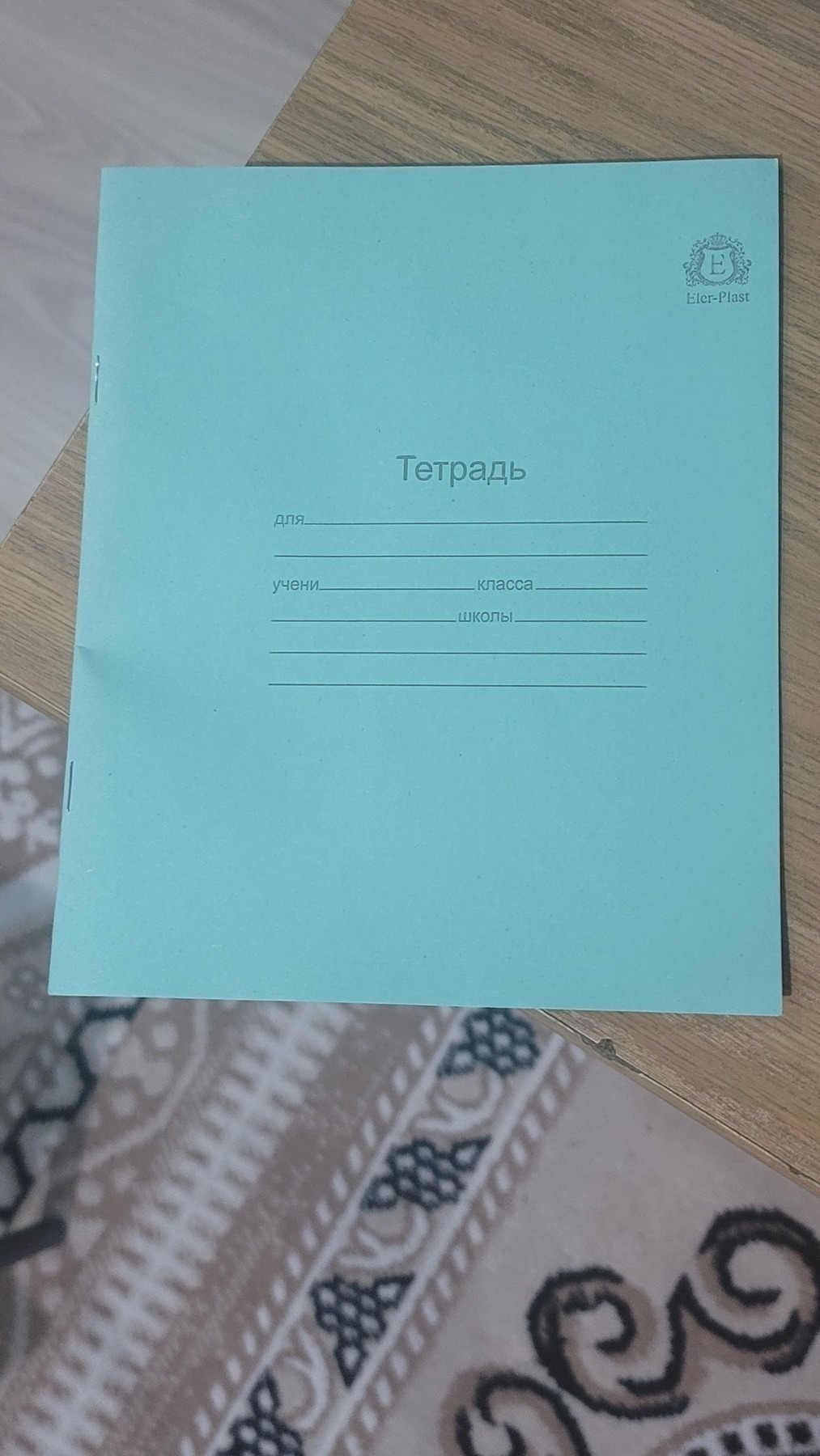 green paper notebook with тетрадь written on the front ("notebook" in Russian)