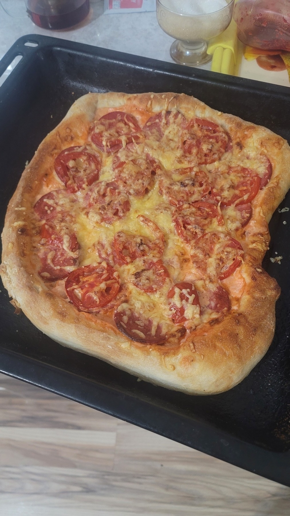 freshly baked pizza with tomatoes, sausage and cheese on an oven shelf