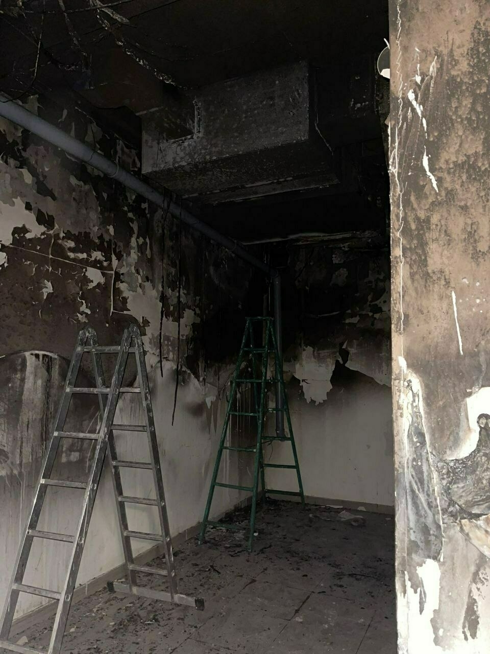 small room with fire damage on the ceiling and upper half of the walls, which are black
