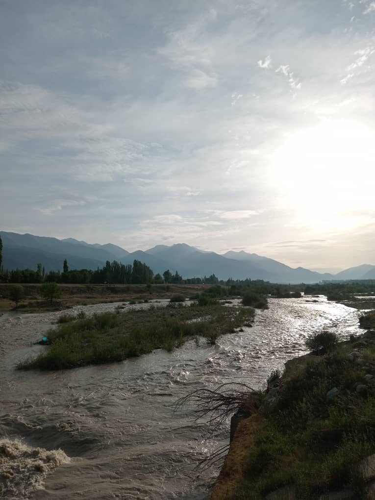 flowing gray river at morning moving towards mountains in distance