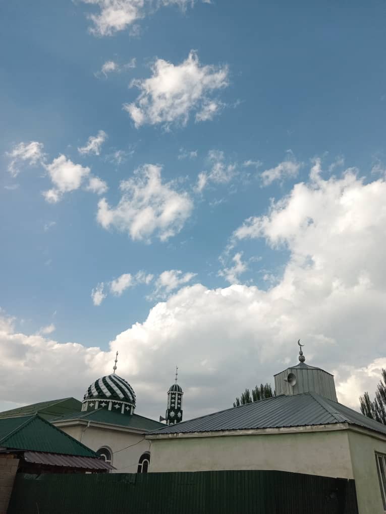 small white building with a gray roof, two small green and white domes and crescent moon pinnacles 