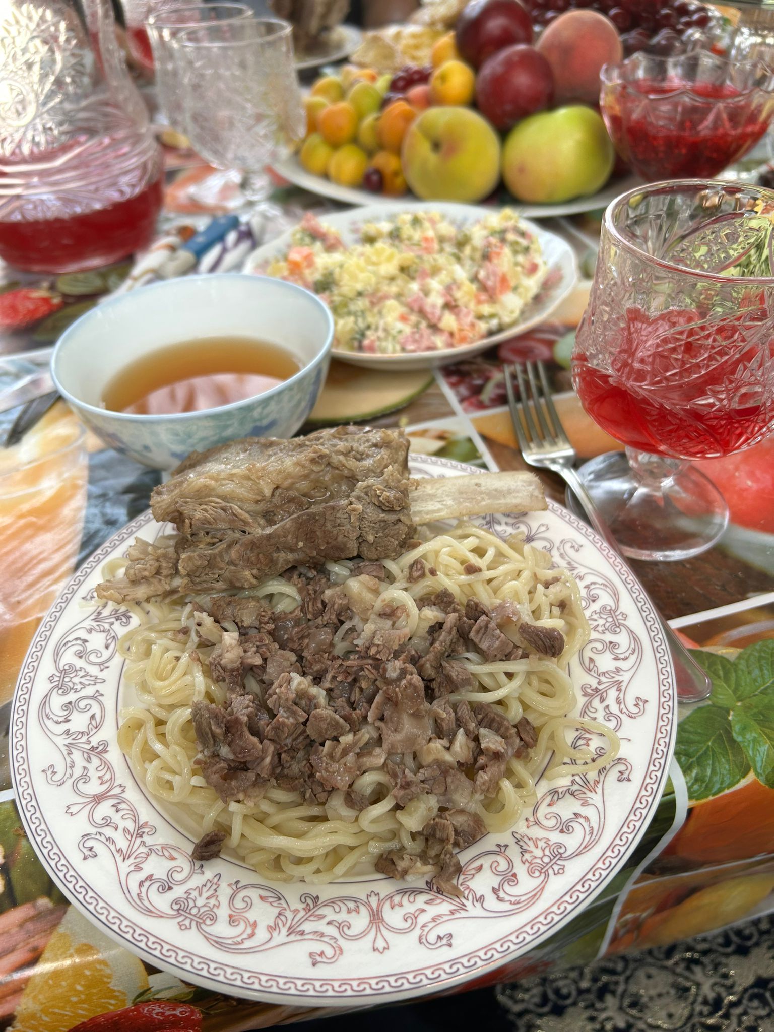 plate of chopped beef mixed into noodles with a portion of beef on a bone to the side 