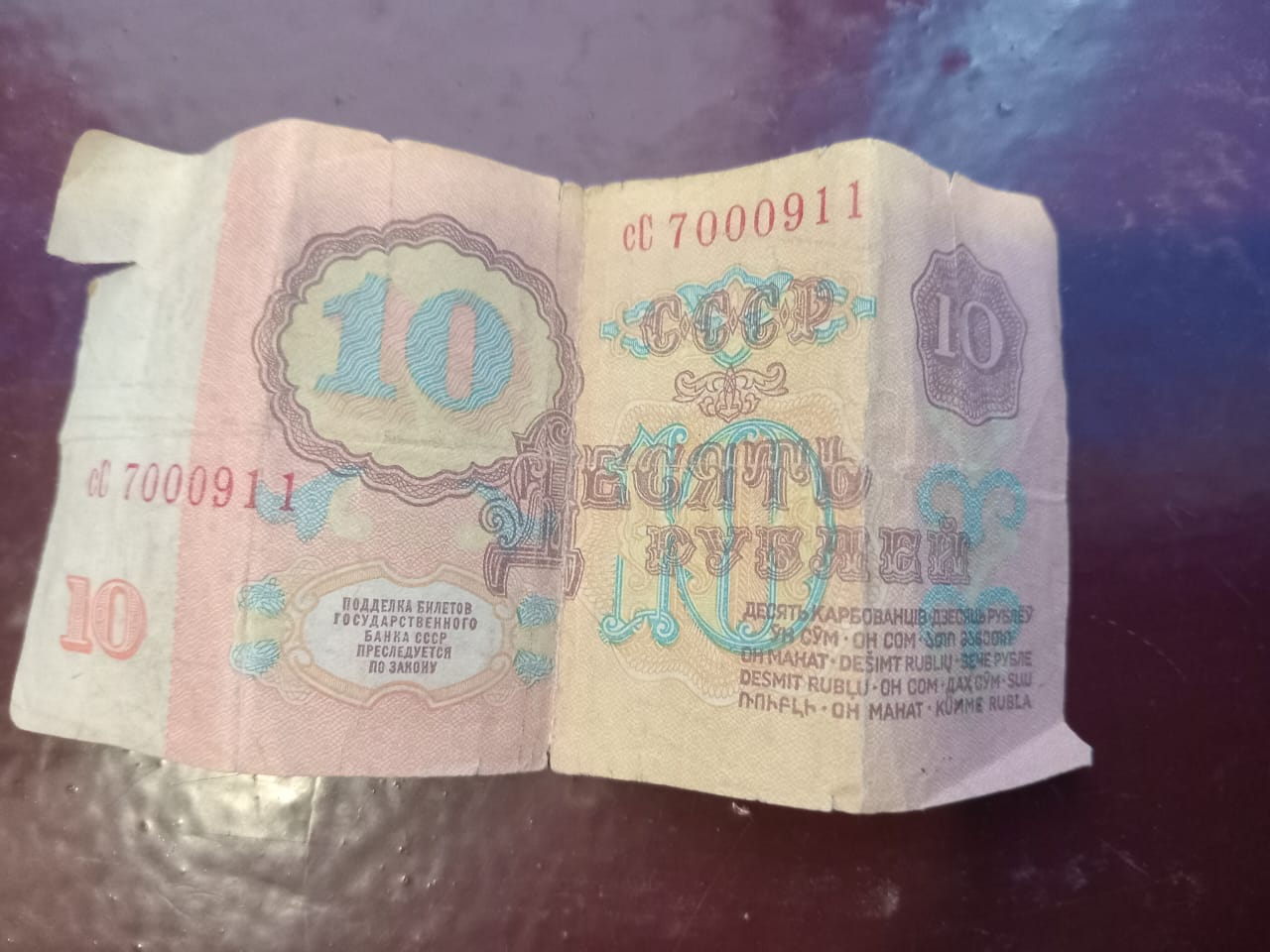 old, creased pink bill that reads '10 rubles, USSR' on it in Russian 