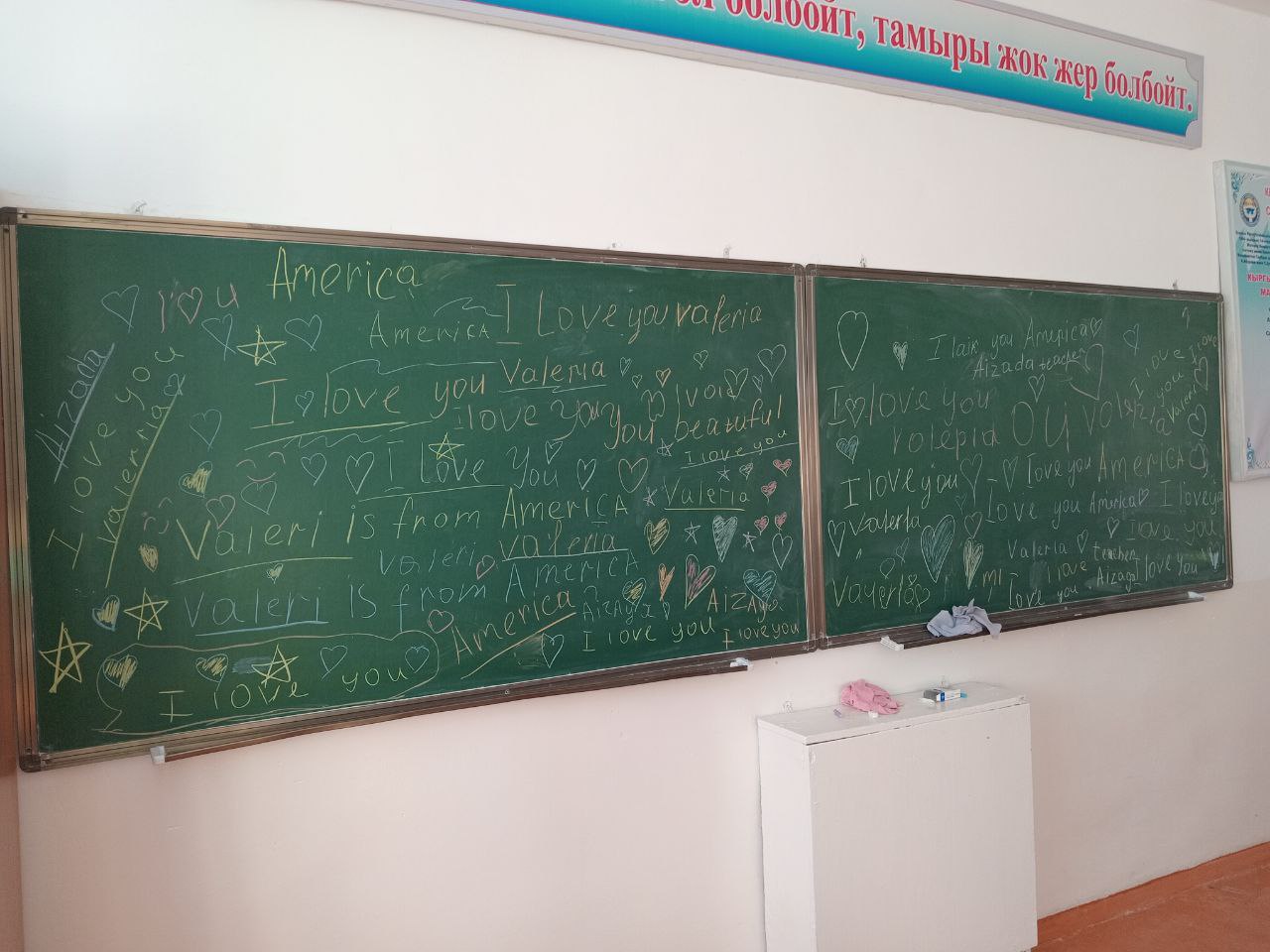 two chalkboards side by side covered in hearts and English sentences like "I love you", "I love you Valeria", "I love you America" and "I love you Aizada" (my coteacher's name)