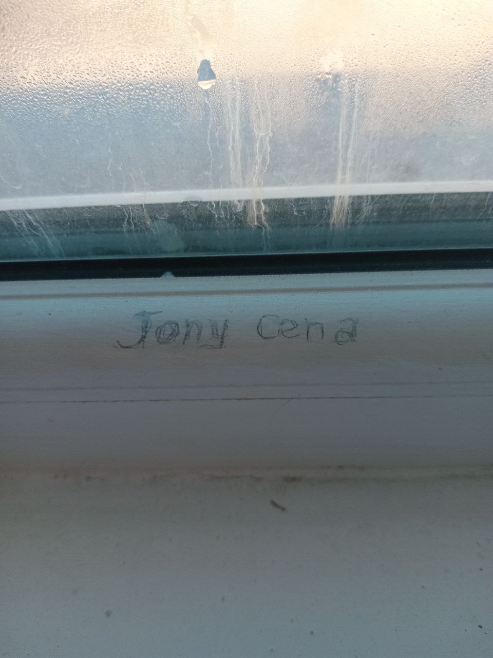 "Jony Cena" written on the bottom of a white windowsill in pencil 