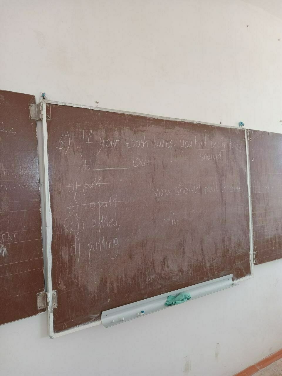 blackboard with a sentence on it: If your tooth hurts, you should have it __ out. Answers are variants of "pull", and the correct answer is "pulled"