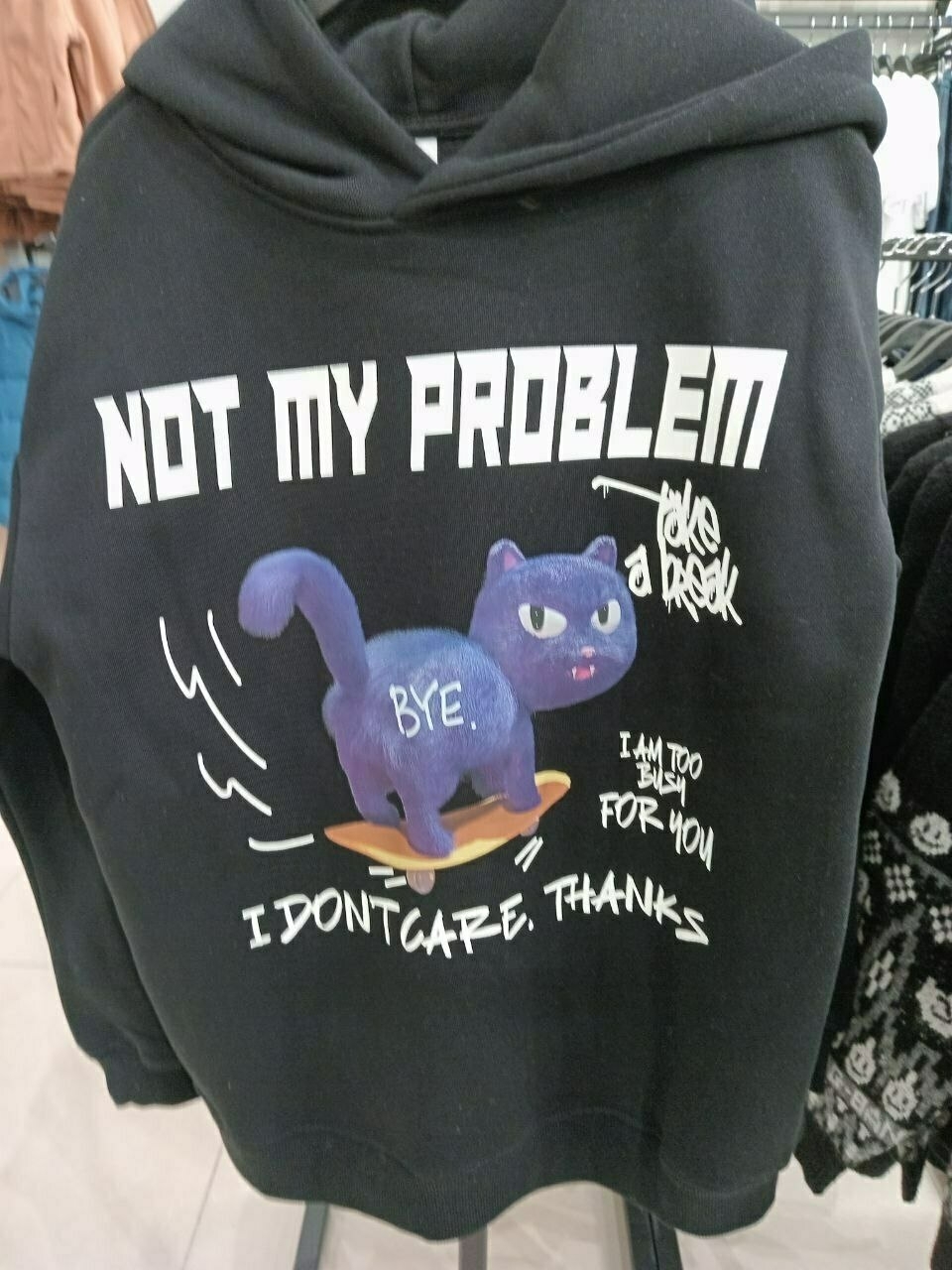 black hoodie with a blue cat skating away on a skateboard. white text: "Not my problem", "Take a break", "Bye.", "I am too busy for you", "I don't care, thanks"