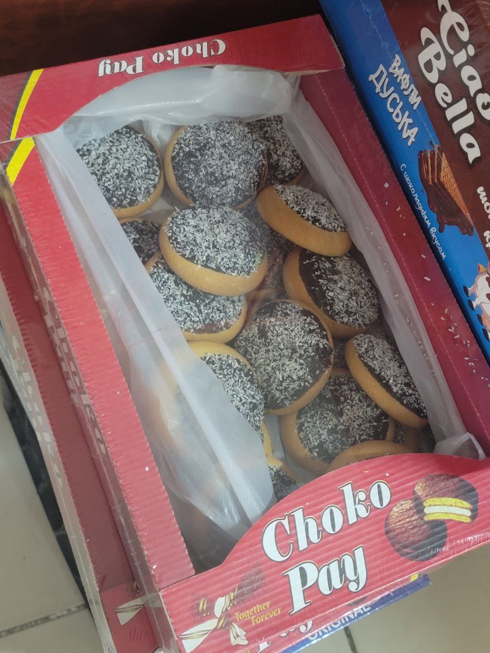 red box with a picture of a layered chocolate and cream cookie and text "Choko Pay" on it; able to see cookies through plastic in middle which are topped with chocolate cream and powdered sugar but look nothing like the box's picture