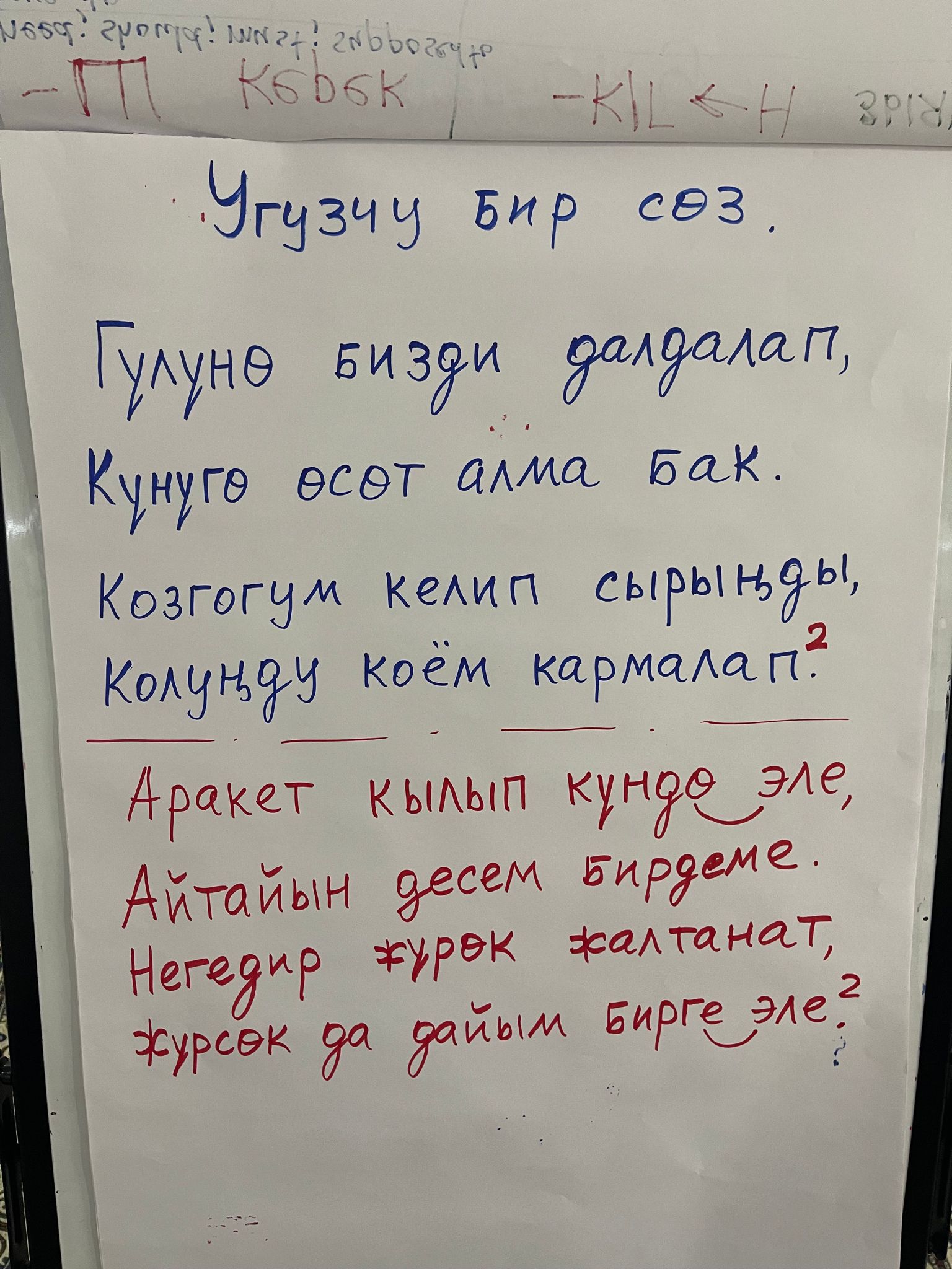 song title and lyrics in Kyrgyz on an easel paper pad