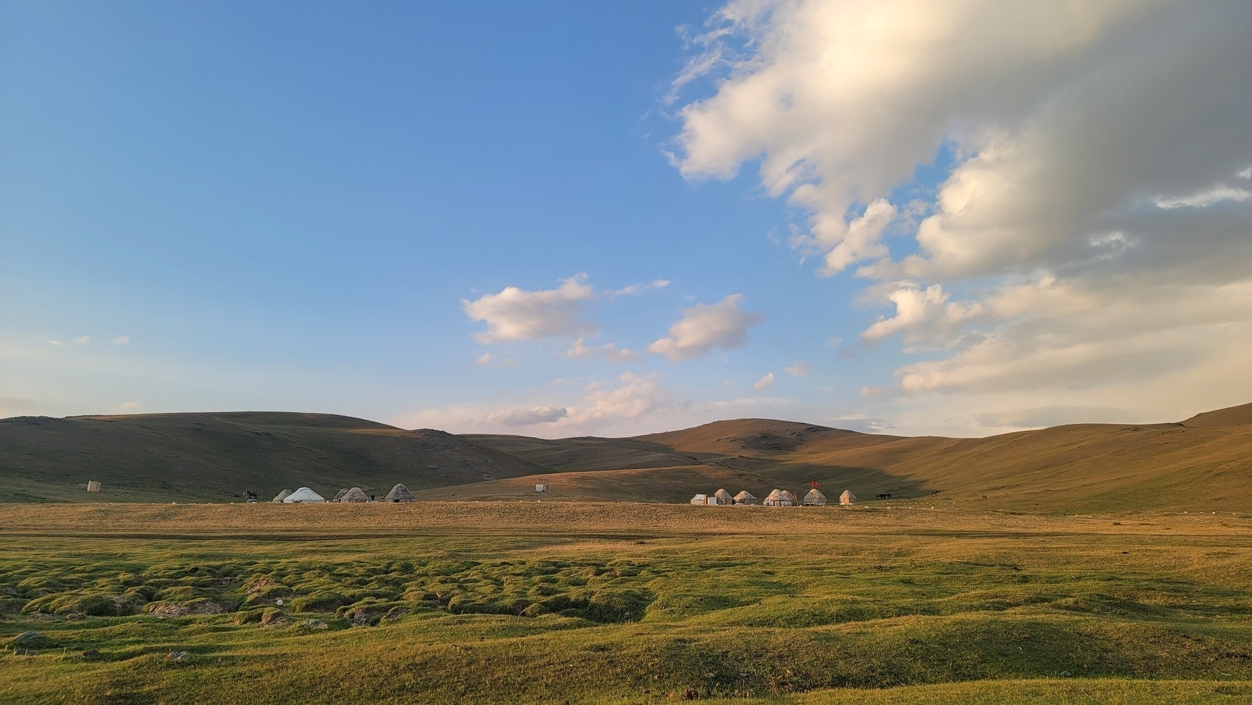 two groups of yurts in front of small hills 