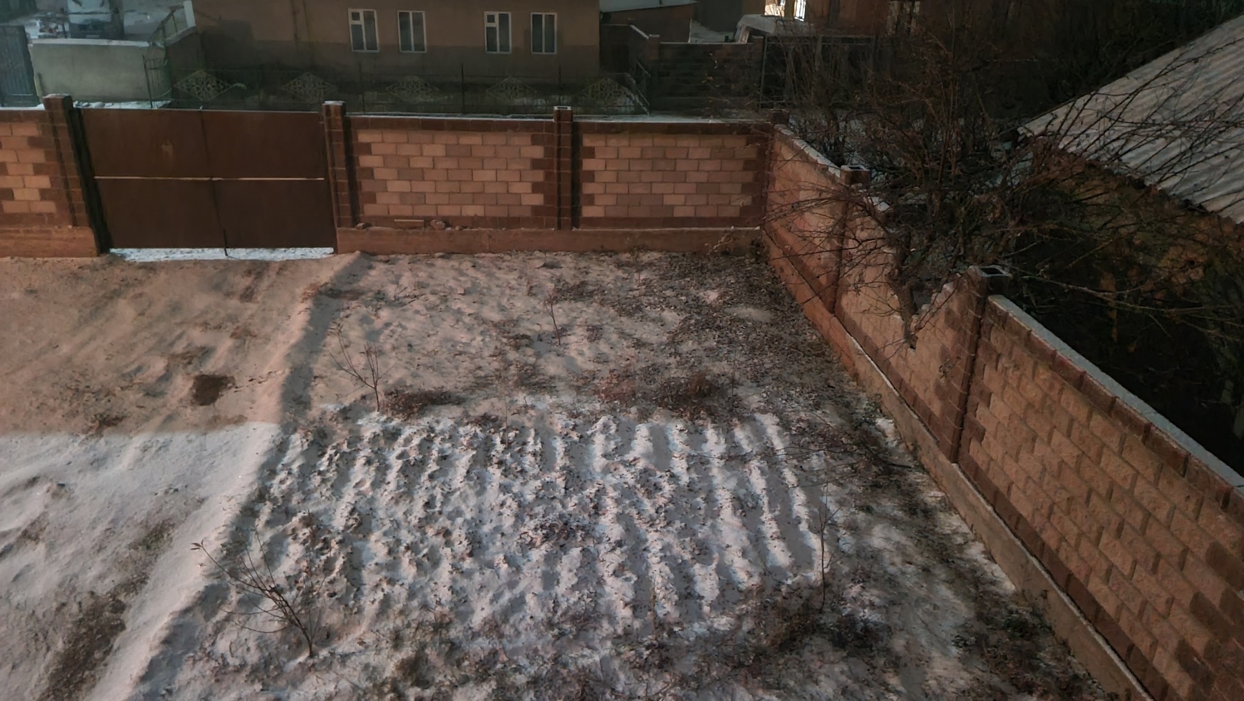 looking down onto snow on a garden and driveway from the second floor