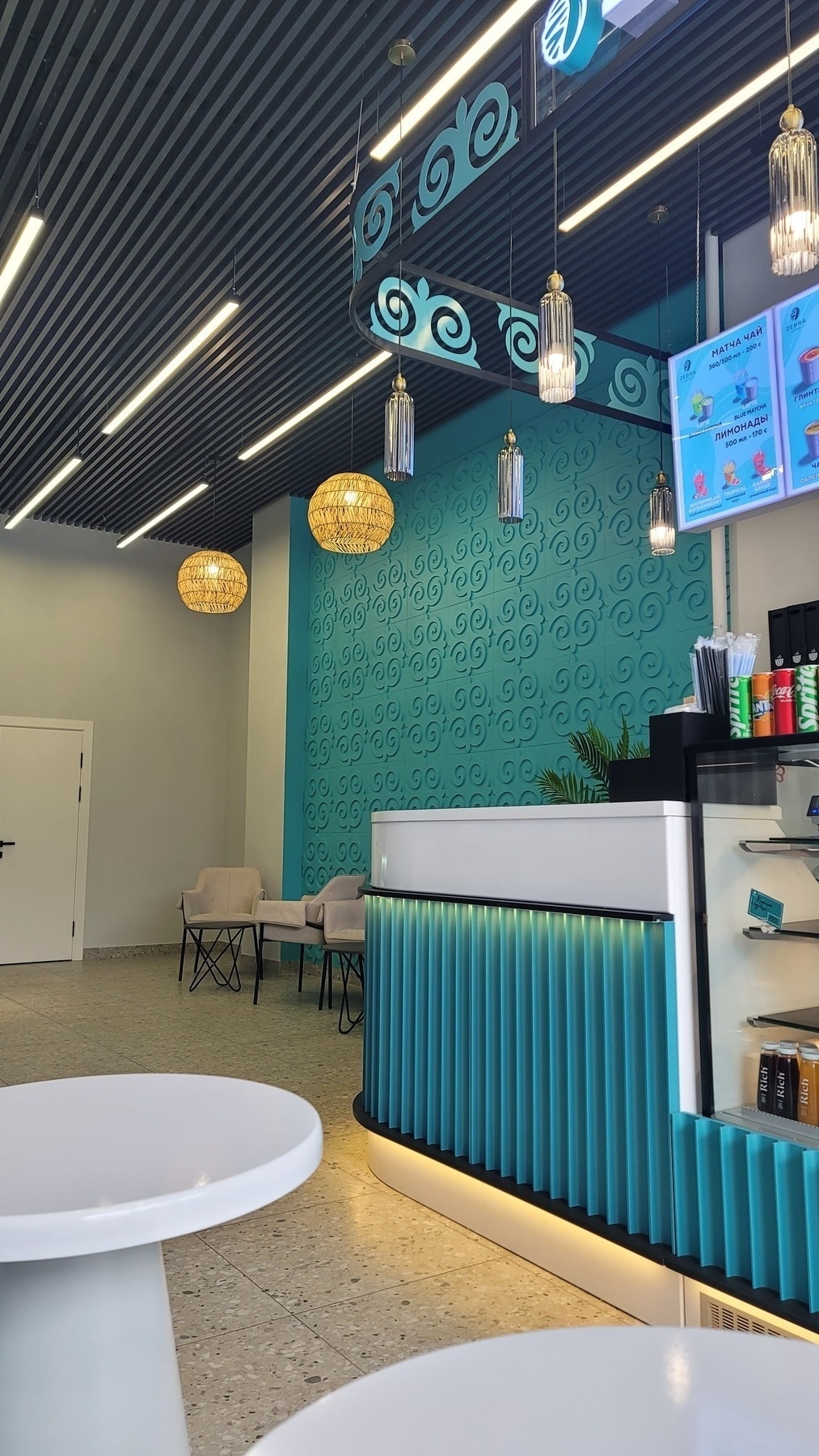 cafe with a teal accent wall, white tables and chairs, tan flooring and a counter in the same teal and white colors
