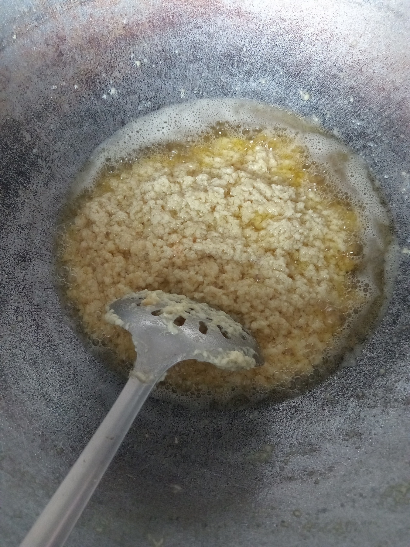 Milk fat frying in oil in a large, gray wok-like pot