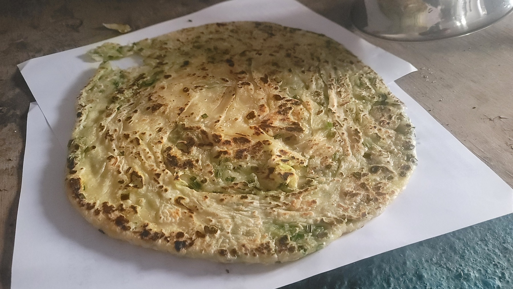 fried flatbread with green onion on a white paper