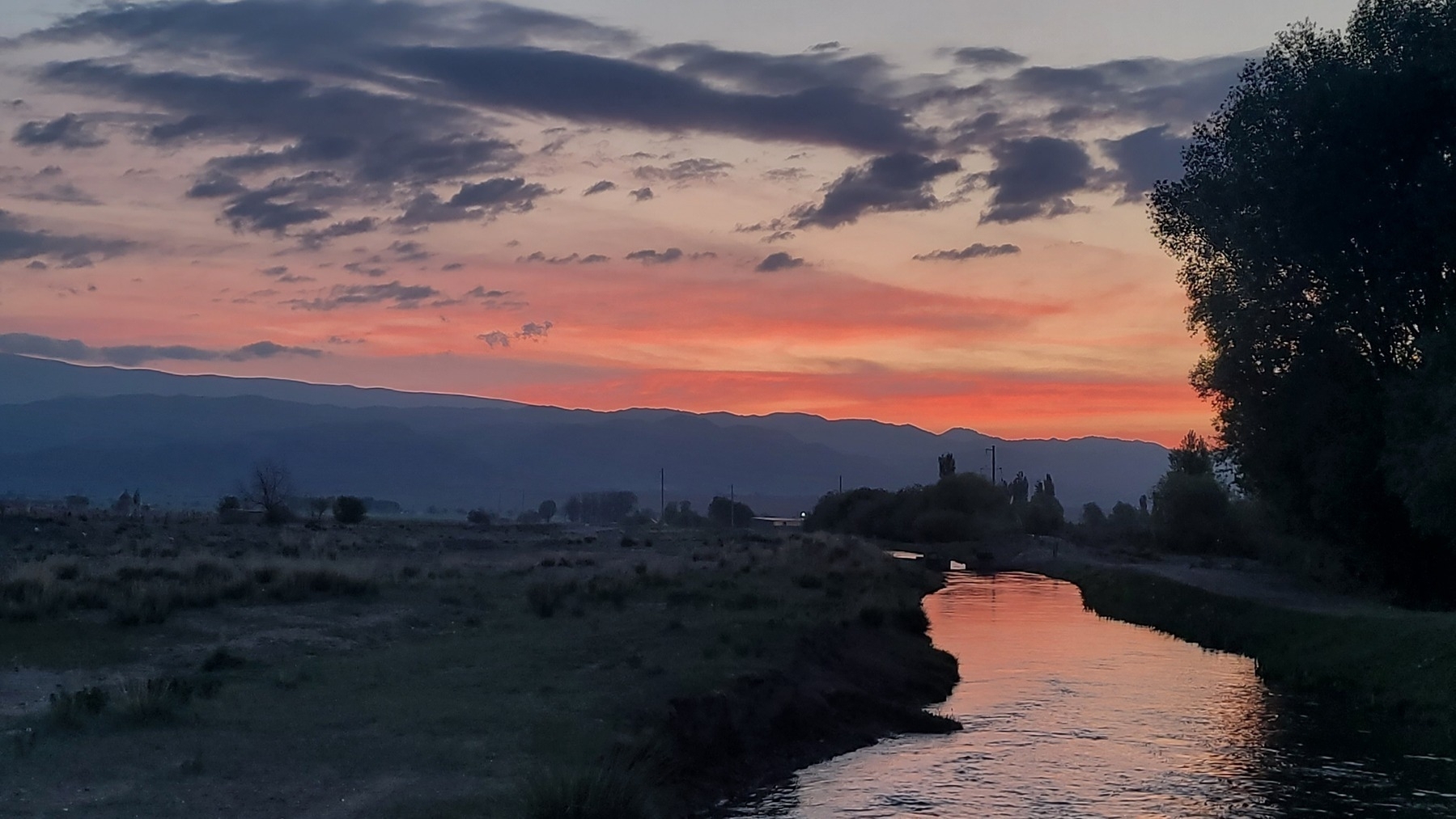 orange/pink sunrise reflected in the water of a small canal