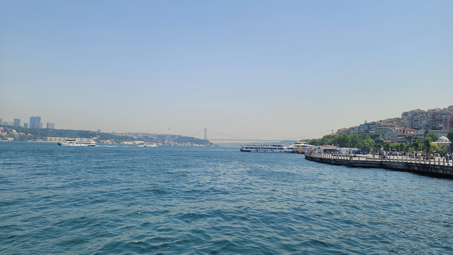 bridge over the sea connecting two islands with trees and buildings