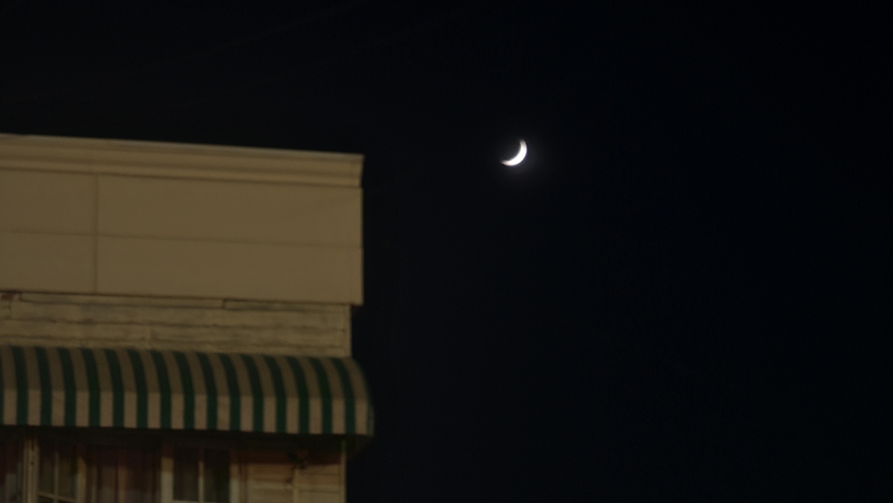 moon in the sky next to a storefront