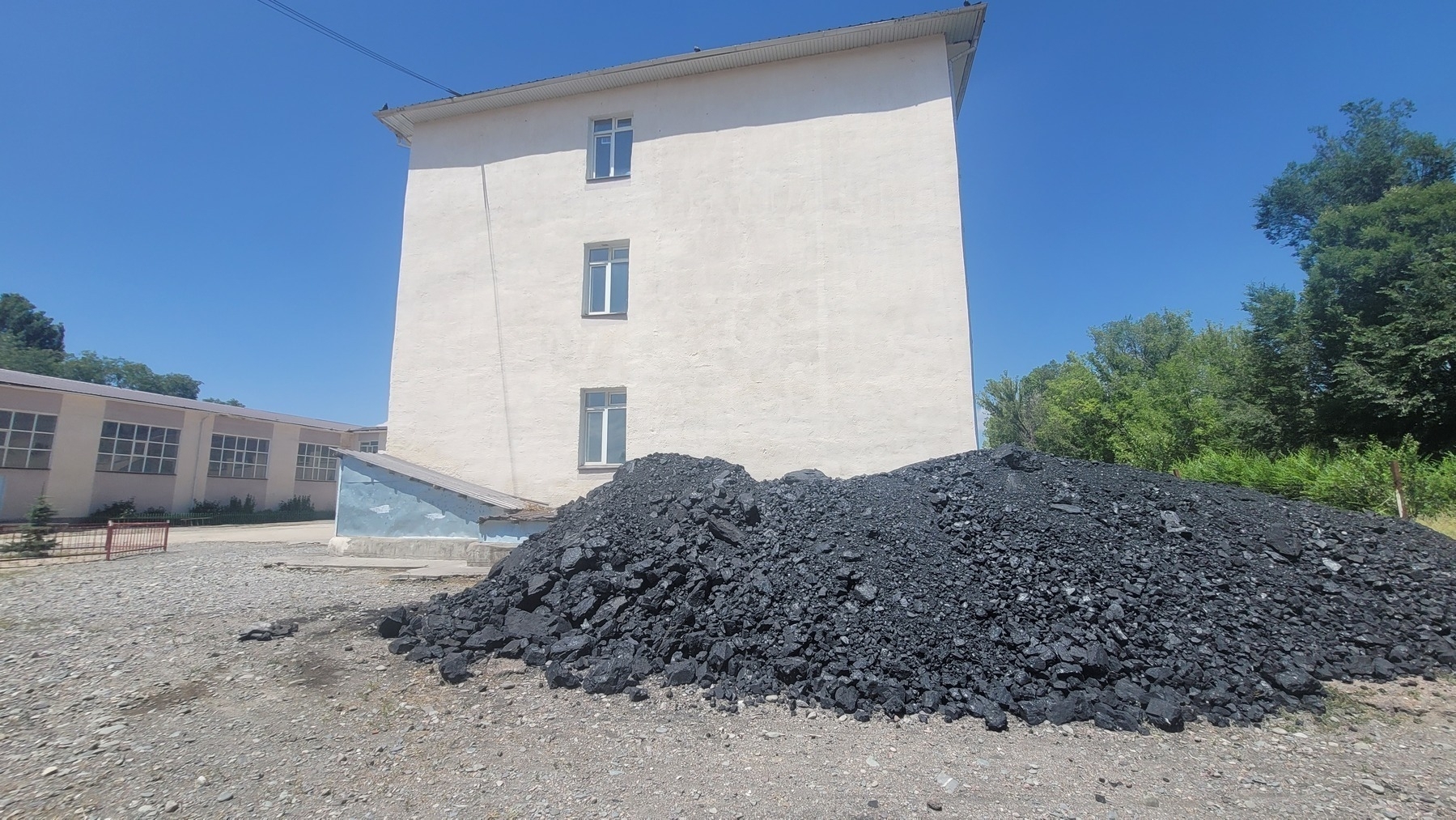 large pile of coal beside a light-colored school building