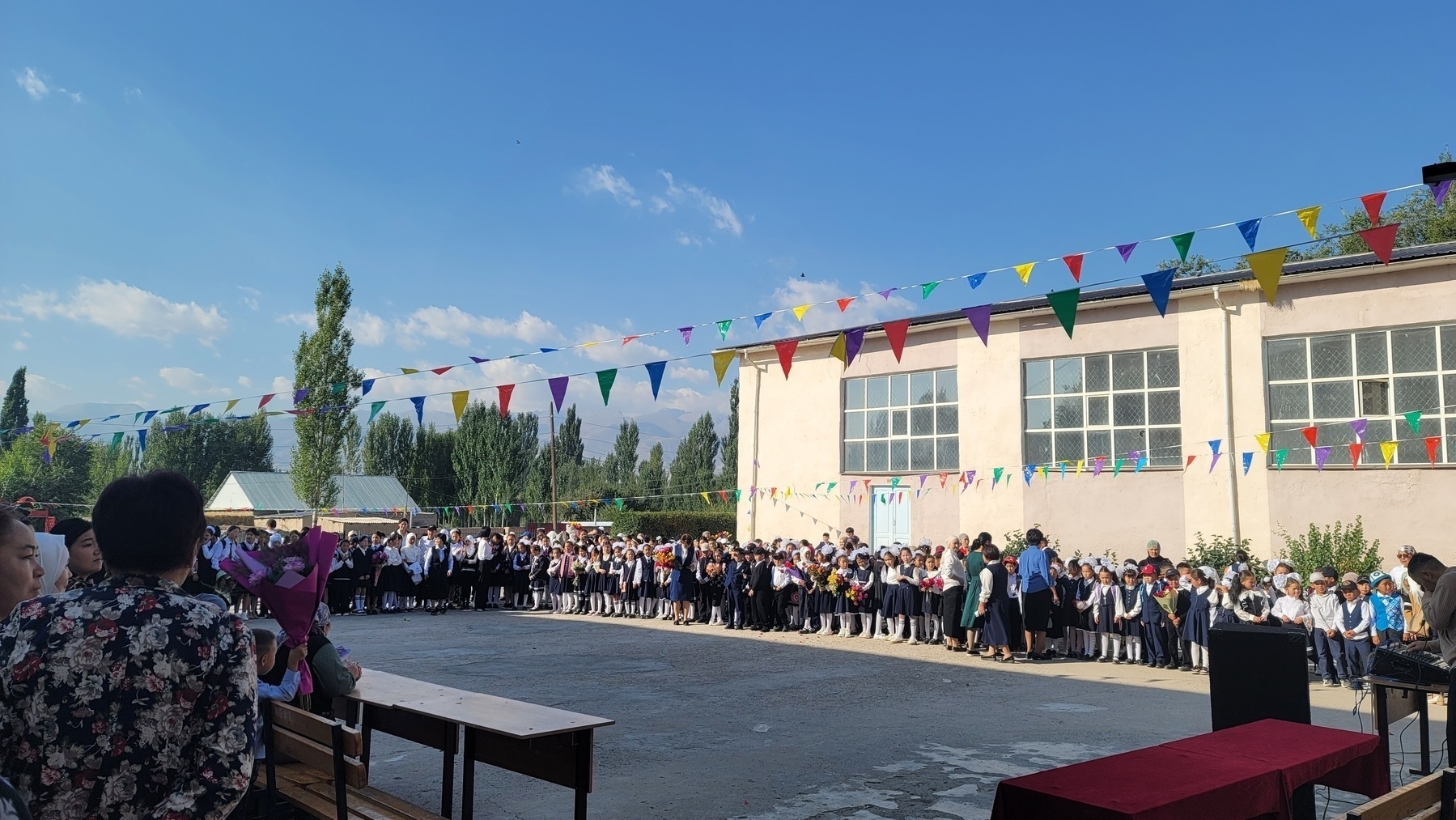 students standing around a rectangular area outside the front of a school