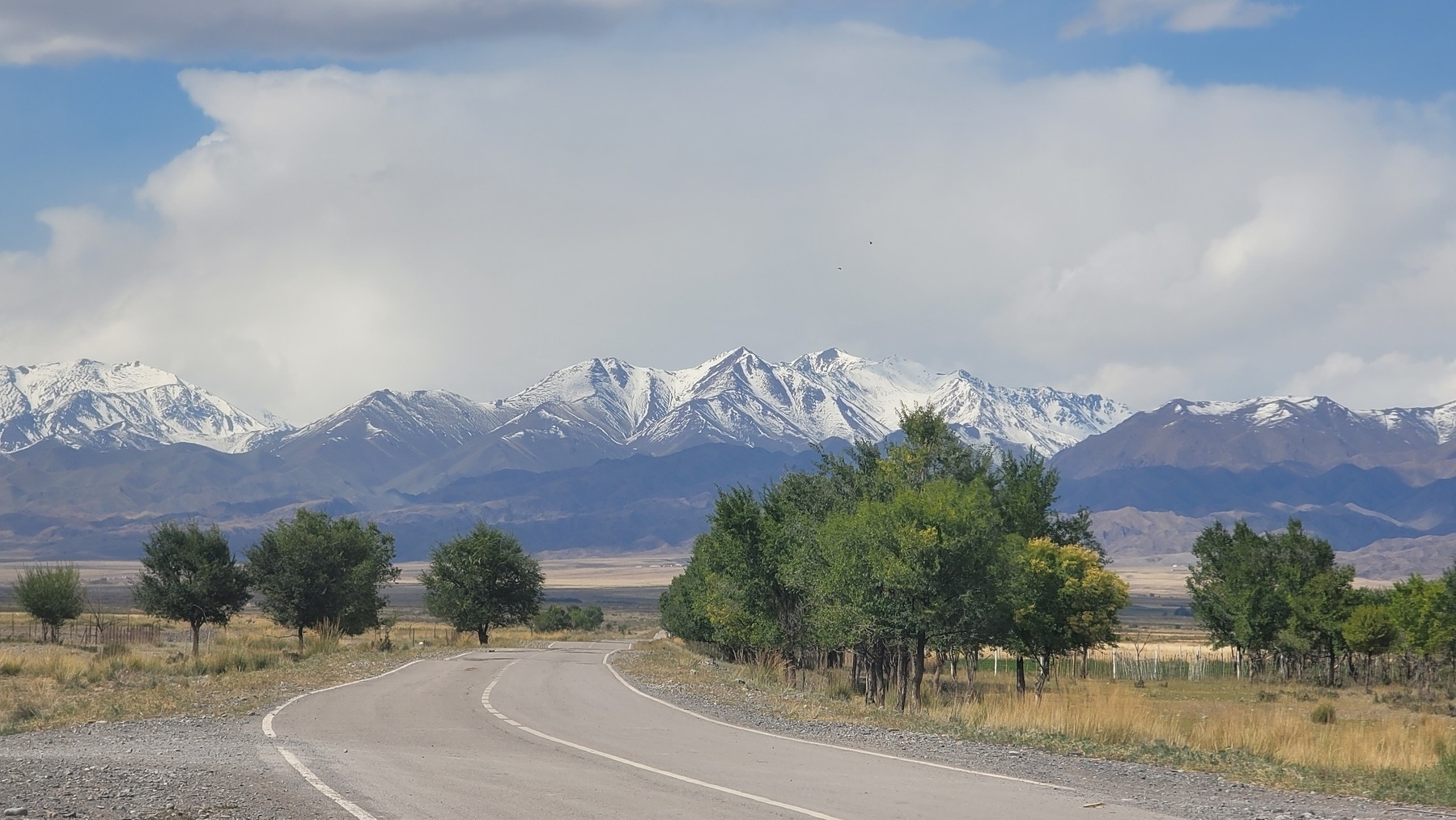 bend in a road going towards snow-capped mountains 