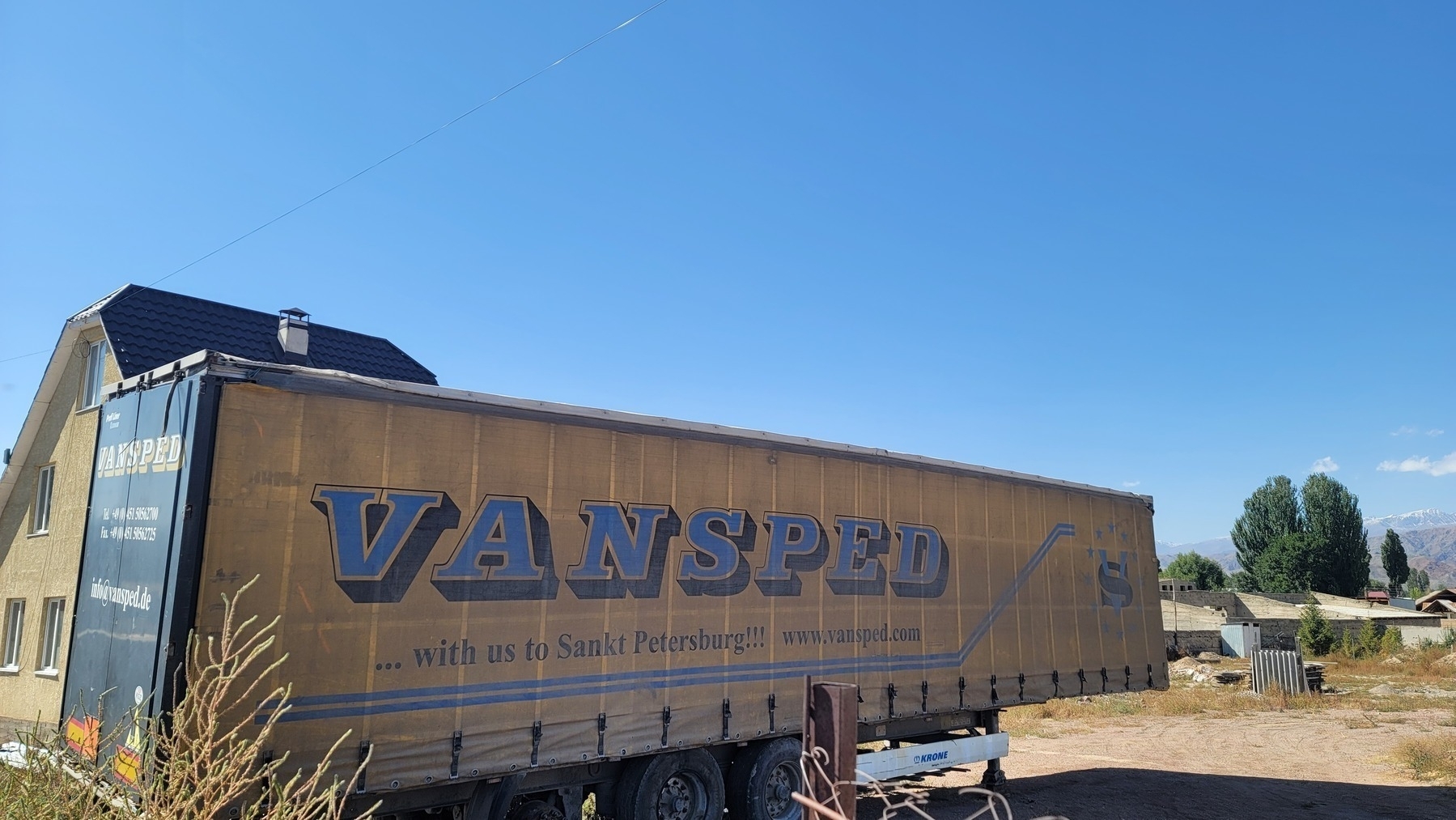 parked, yellow Vansped truck container with text "...with us to Sankt Petersburg!!! www.vansped.com"