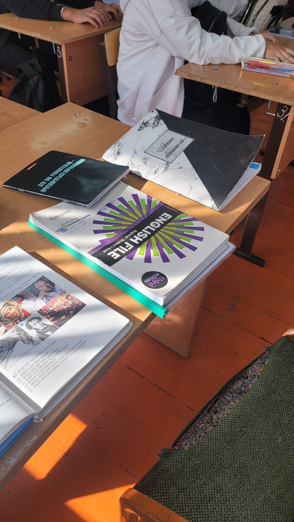 teacher's desk with two English textbooks (one open, one closed) and two notebooks,