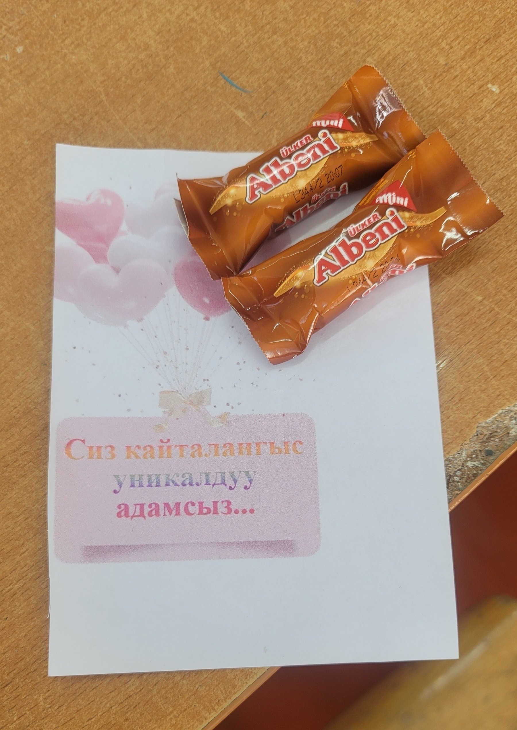 two mini Albeni chocolates taped to a paper with Kyrgyz words which translate to 'you are a unique person'