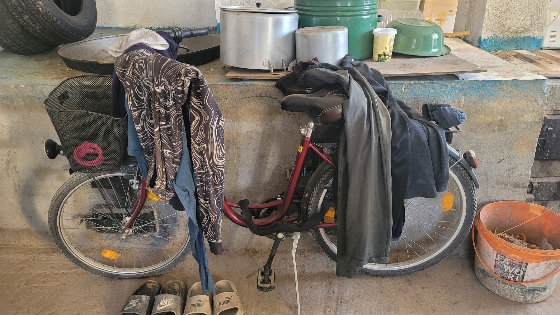 bike with jackets draped on it against a concrete oven