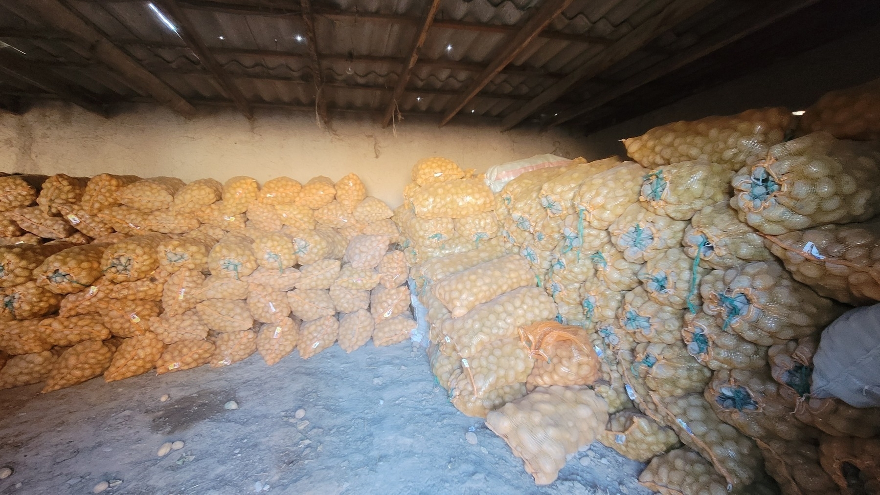 sacks of potatoes stacked inside of a barn