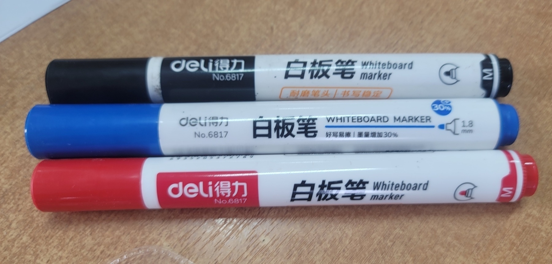 black, blue and red Deli (得力) Chinese brand dry erase markers on a desk