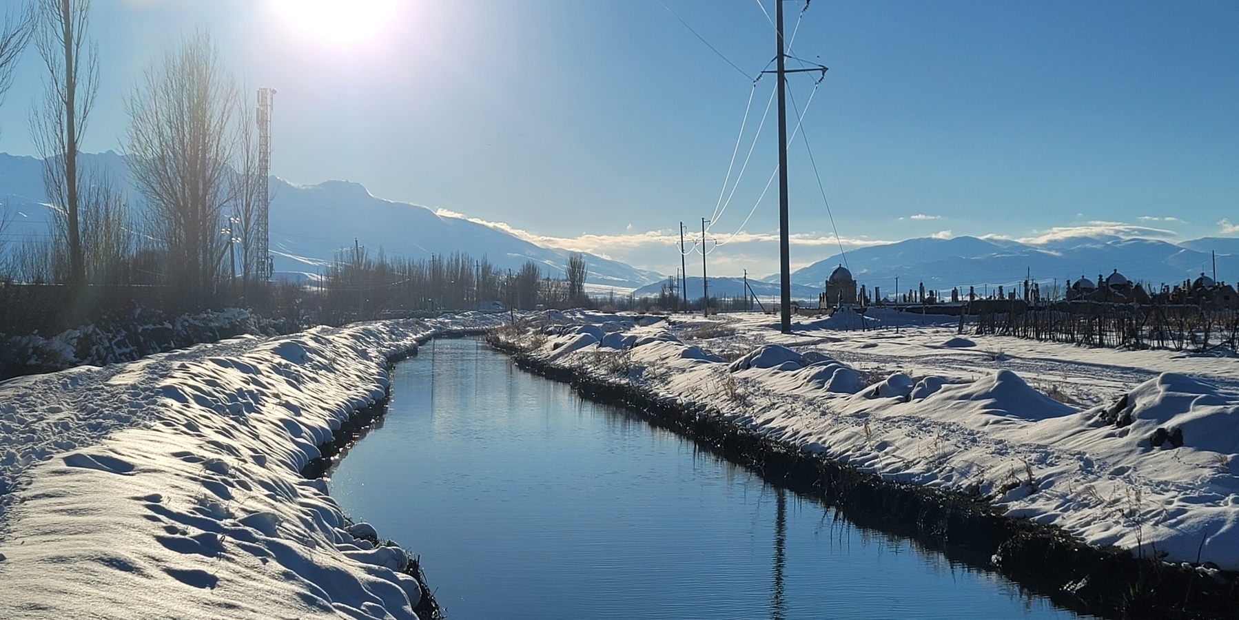 village canal with snow on either side on a bright day