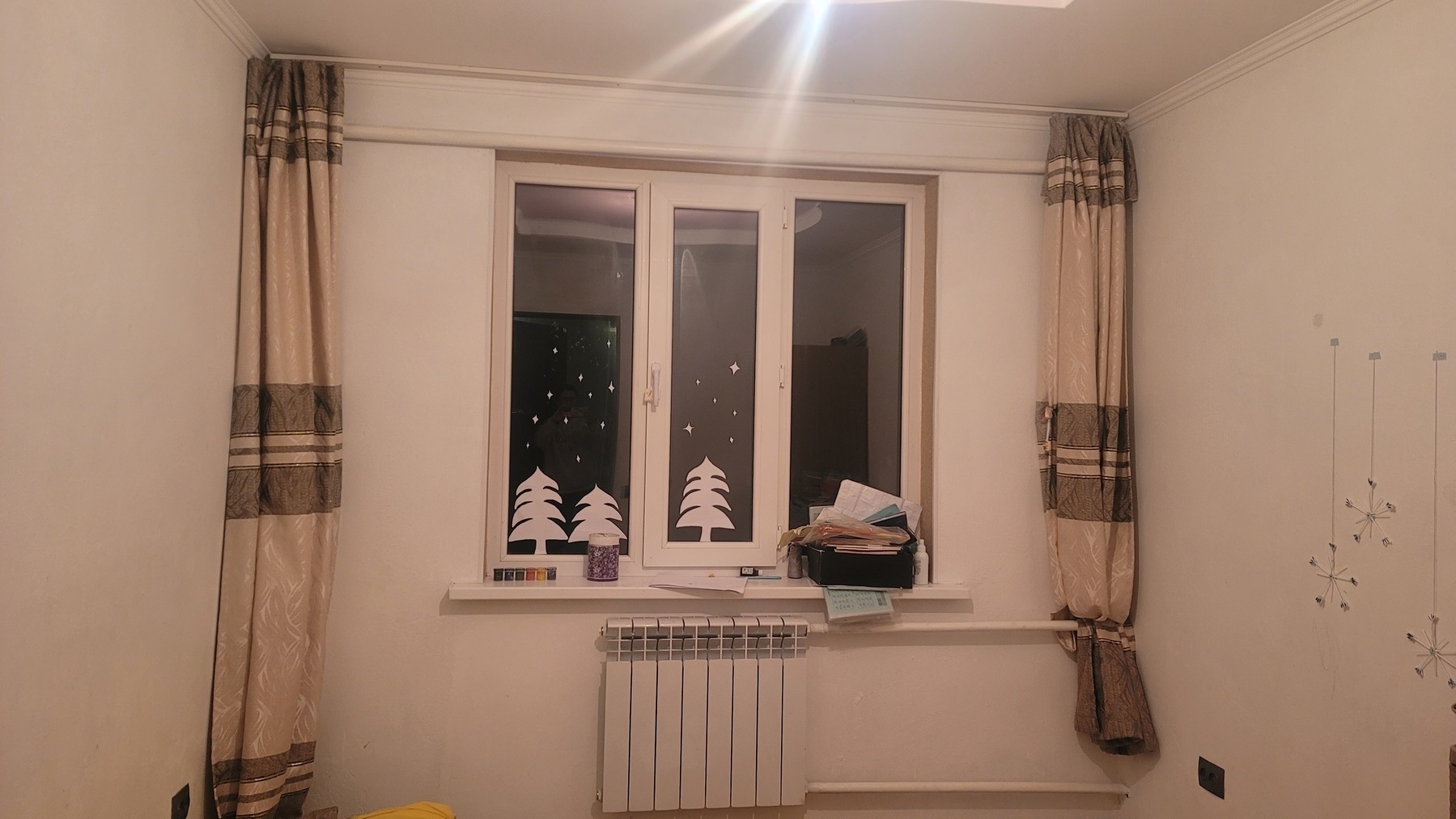 room. paper trees and stars on the window. 3 craft snowflakes on the wall