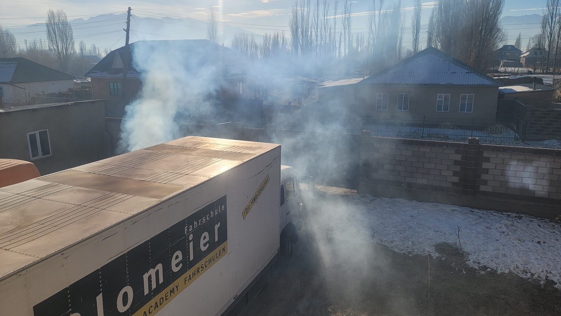 looking down at a small semi-trailer truck, with exhaust in the air around the front