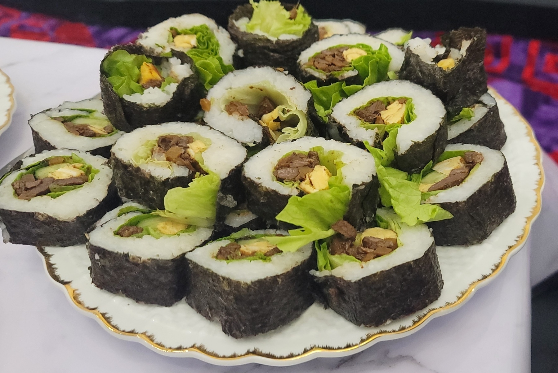plate of sushi rolls filled with meat, egg and lettuce