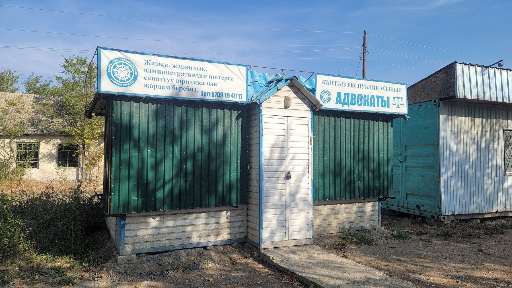 small blue, green and white building which looks more like an outdoor storage shed than an office