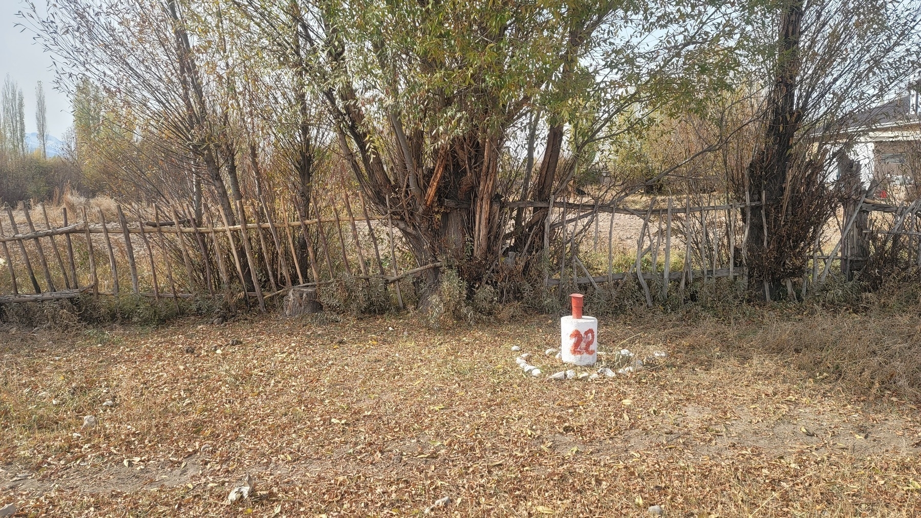 small concrete cylinder painted white with a red 22 on the ground with a red cylinder on top. rocks around the base of the cylinder 