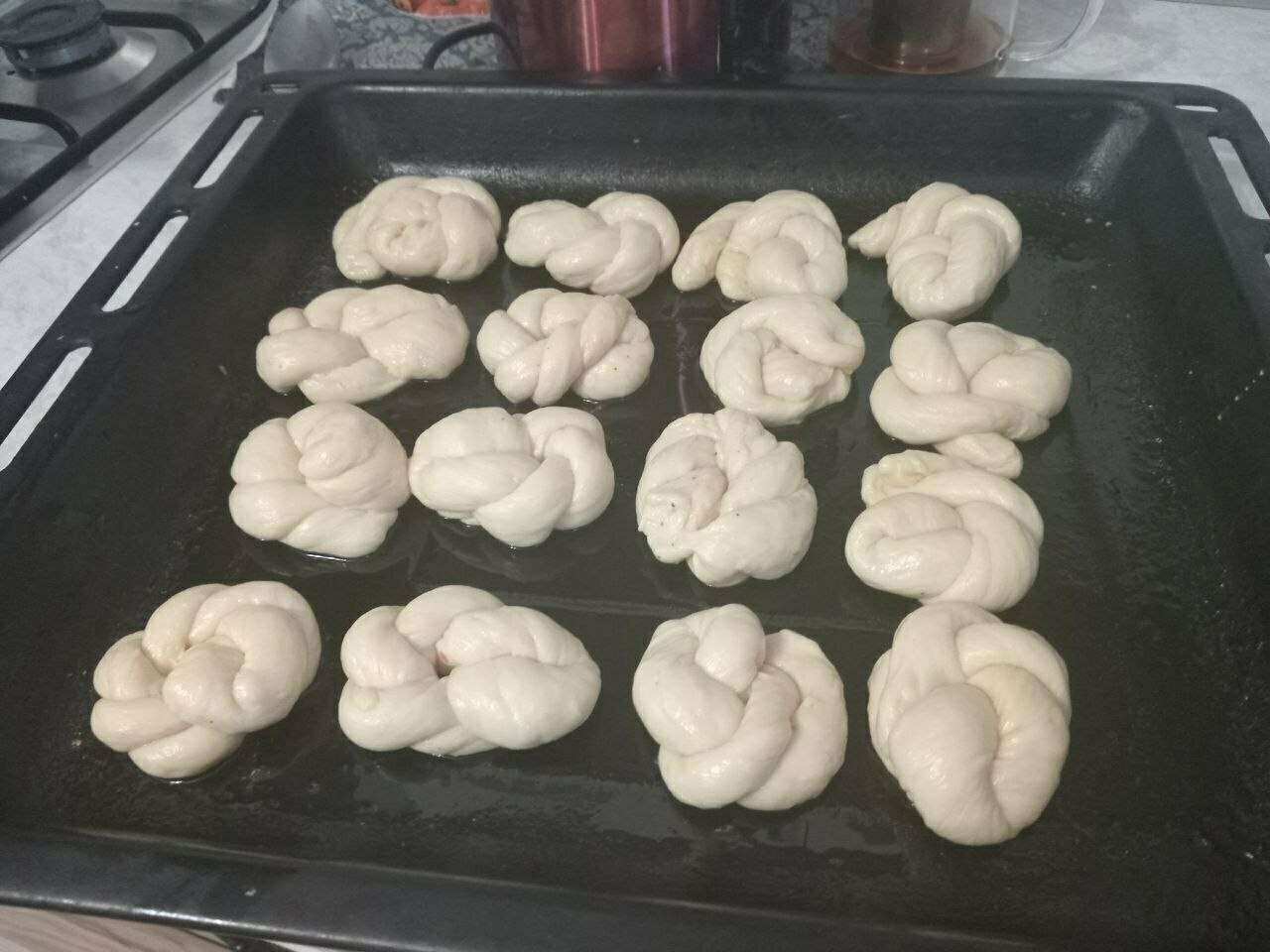 16 folded buns on a black oven tray